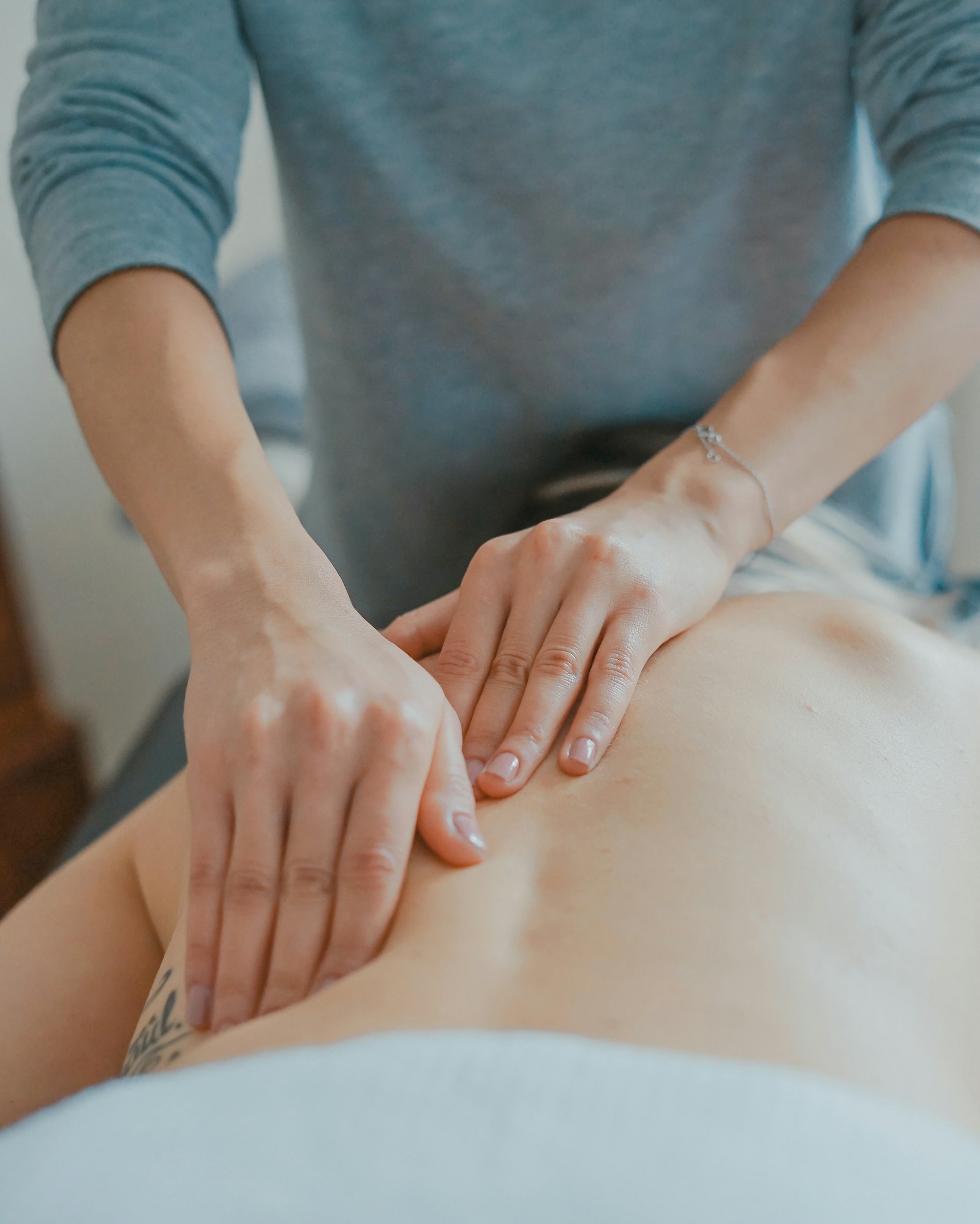 Séance de soin — mains en contact avec le dos, geste apaisant